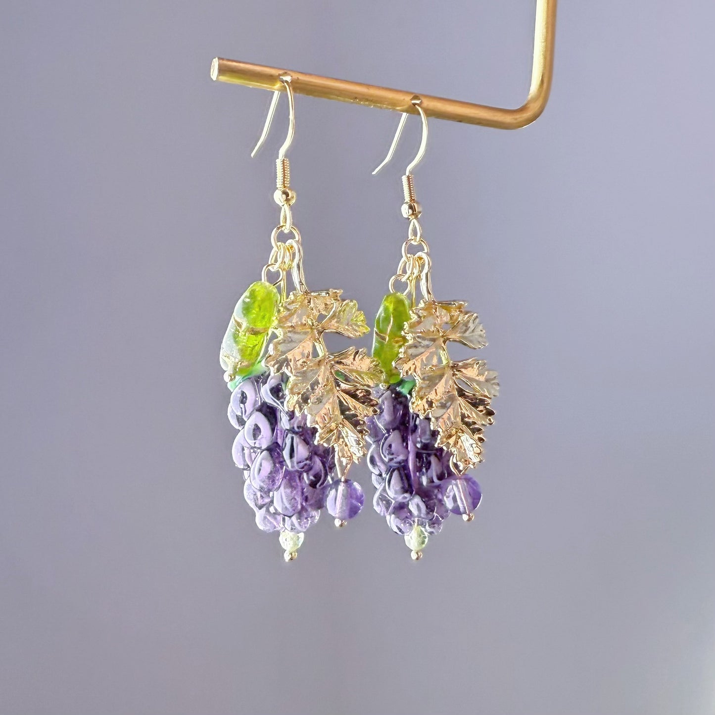 Pair of earrings with purple and green beads on a gray background