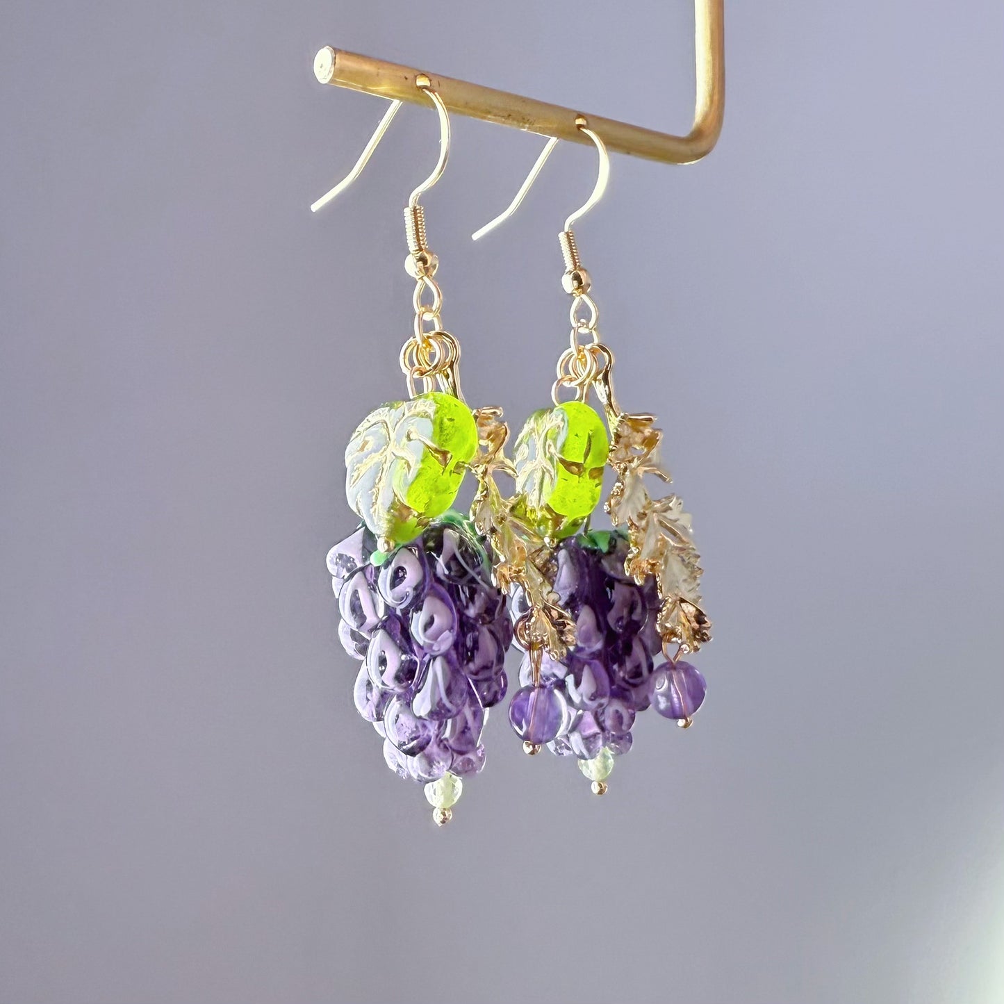 Pair of earrings with purple and green beads on a gray background