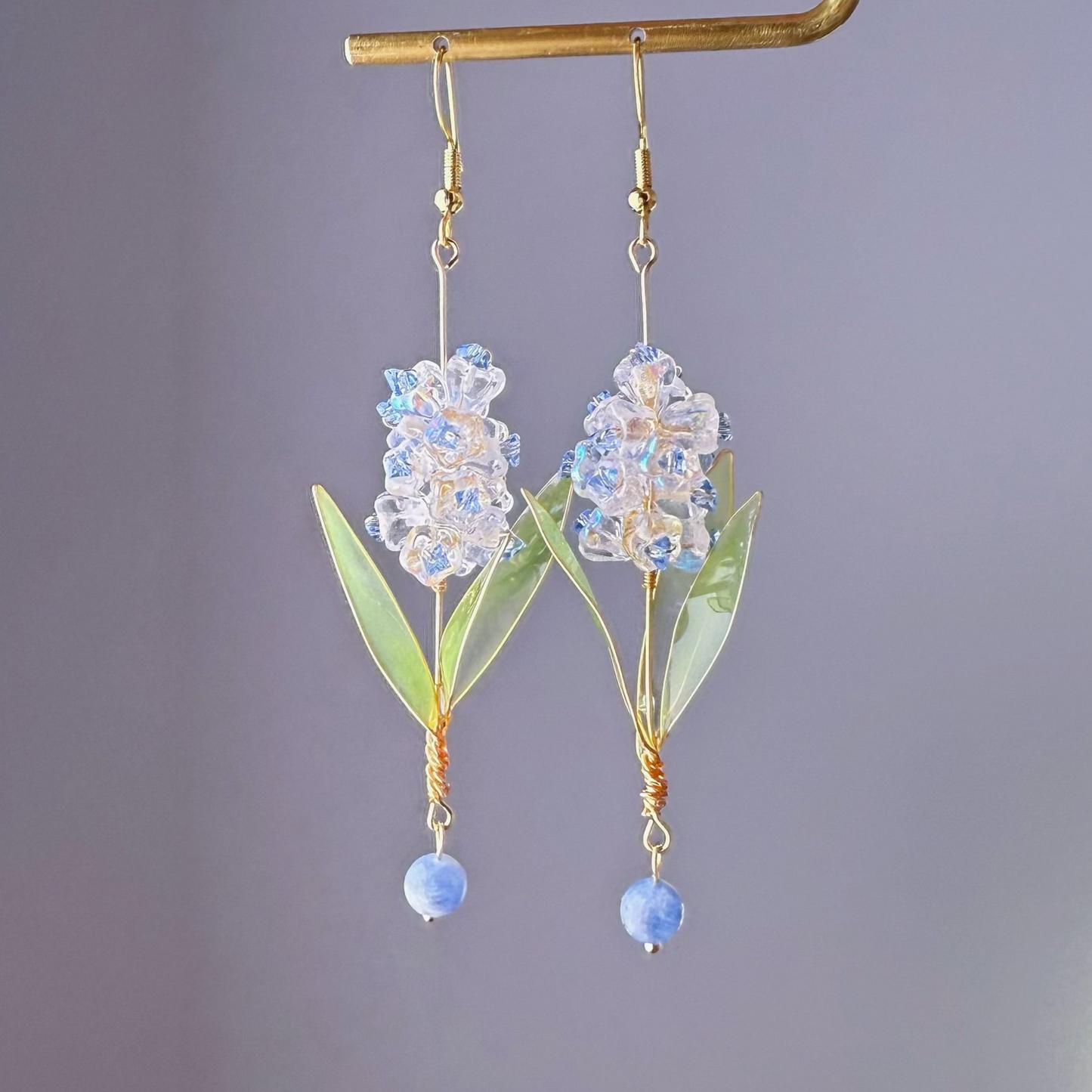 Decorative earrings with floral design and blue beads on a gray background
