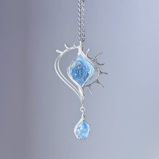 Silver necklace with a blue pendant on a gray background