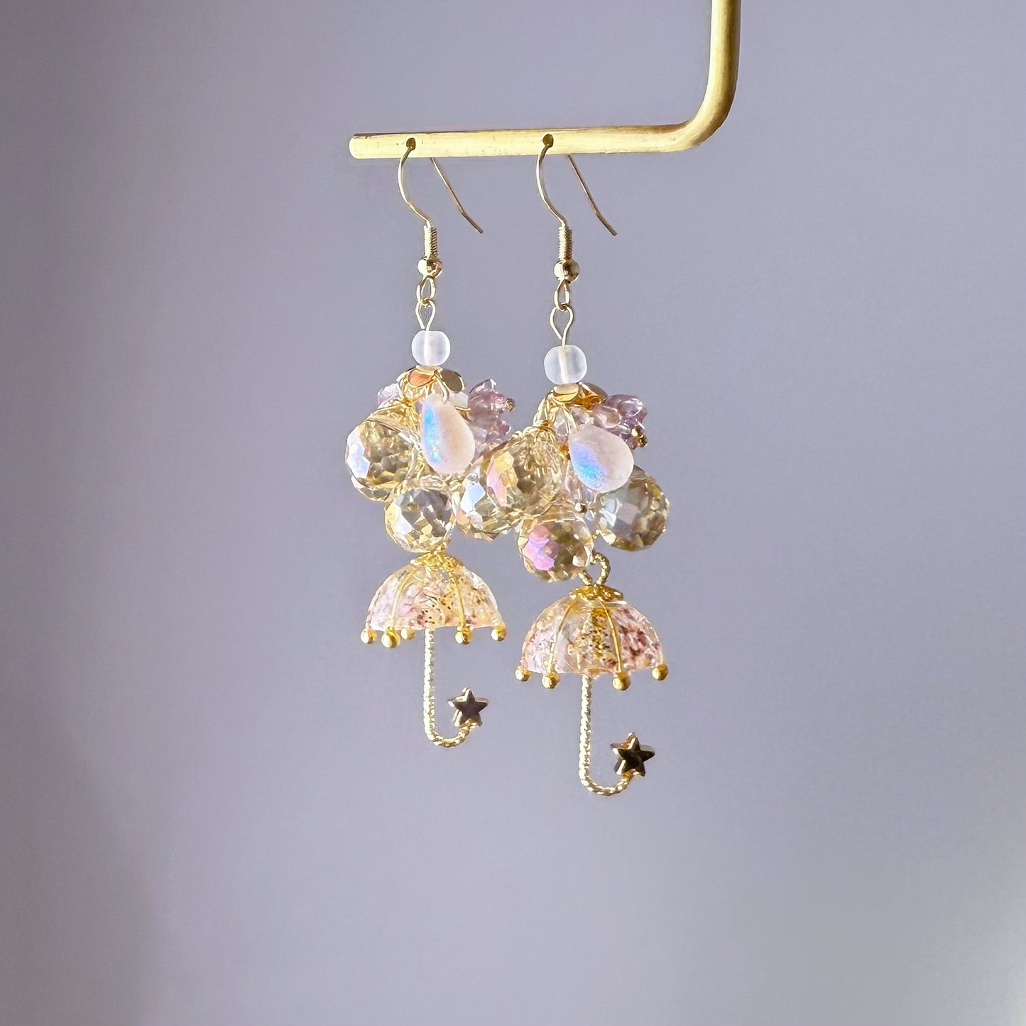 Decorative earrings with umbrella and star designs on a gray background