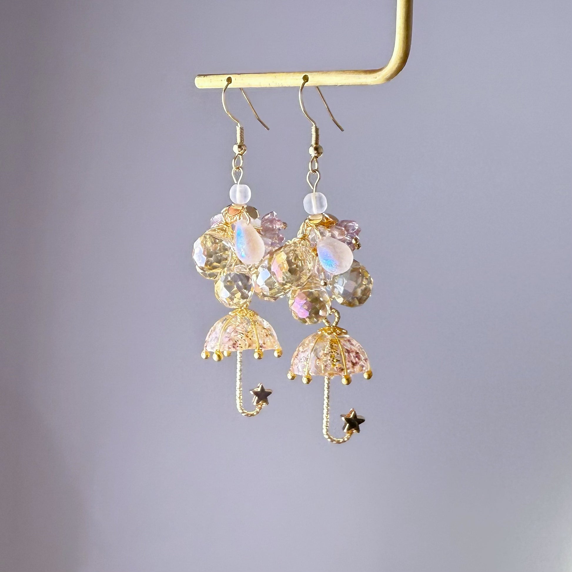Decorative earrings with umbrella and star designs on a gray background